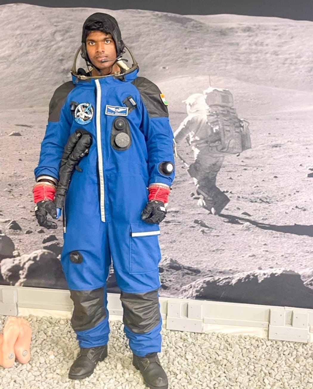 Sanjay Giridharan in a space suit with Apollo lunar landing backdrop